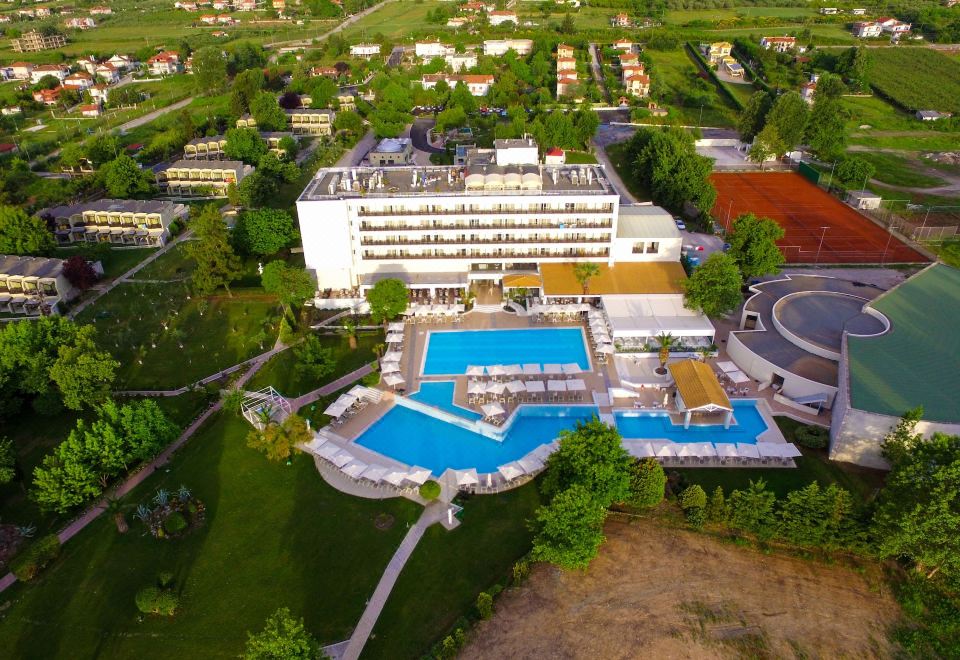 aerial view of a large white hotel surrounded by grass and trees , with a pool visible at Olympian Bay Grand Resort