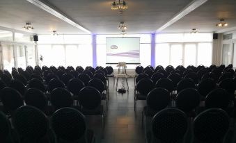 a large conference room with rows of chairs arranged in a semicircle , and a projector screen mounted on the wall at La Cote d'Or