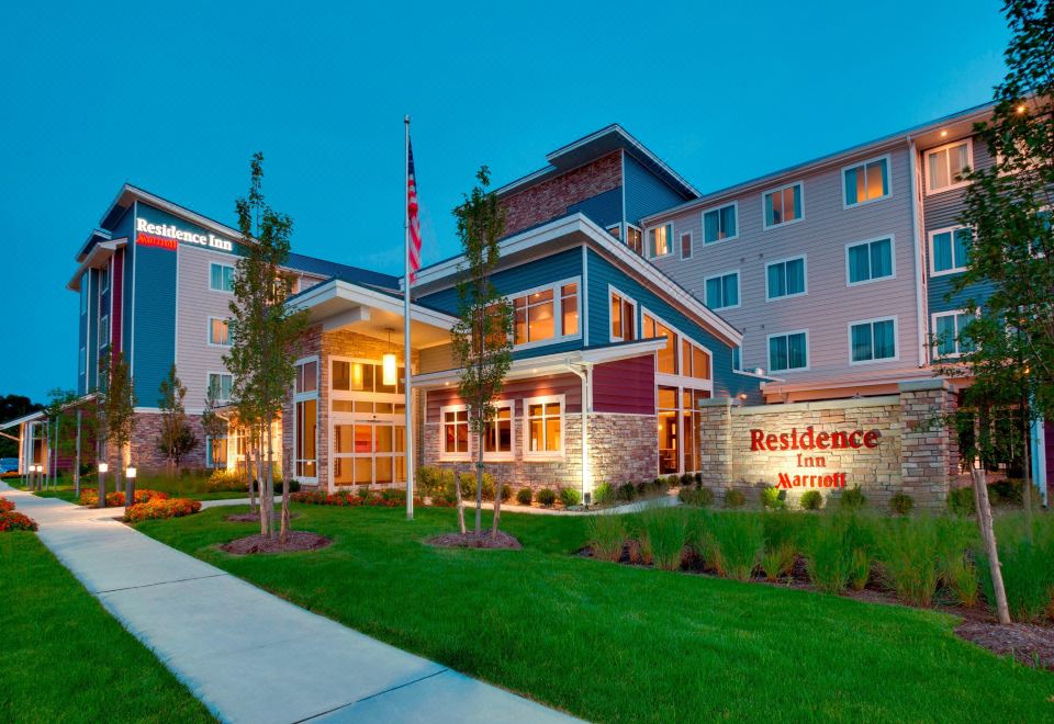 a large brick building with a flag in front of it , surrounded by green grass at Residence Inn Kingston