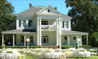 a large white house with multiple tables and chairs set up for an outdoor event at Blythewood Plantation