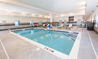 a large indoor swimming pool with a blue and white color scheme , surrounded by chairs and tables at Staybridge Suites Denver North - Thornton