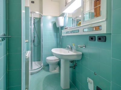 a small bathroom with blue walls and green tiles features a sink , toilet , and shower at Messi