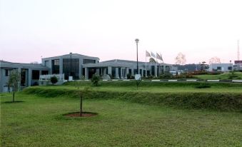 a large , modern building with multiple flags flying in the breeze , surrounded by a lush green lawn and trees at Grand Palace Hotel Mzuzu