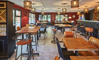 a modern restaurant with wooden tables and chairs , a bar area , and red walls decorated with pendant lights at Kyriad Lille Est - Hem