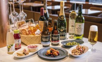 a table is set with various bottles of wine , a basket of food , and wine glasses at Candeo Hotels Omiya