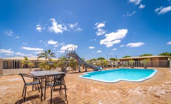 a backyard with a swimming pool , outdoor furniture , and a slide , under a clear blue sky at Carnarvon Motel