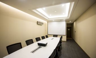 a conference room with a long table , chairs , and a projector screen set up for a meeting at Polaris Hotel