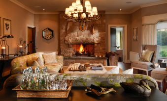 a cozy living room with a fireplace and a dining table , surrounded by chairs and a couch at Ballynahinch Castle Hotel