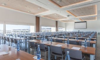 a large conference room with rows of chairs and tables , water bottles , and a projector screen at Zafiro Palace Alcudia