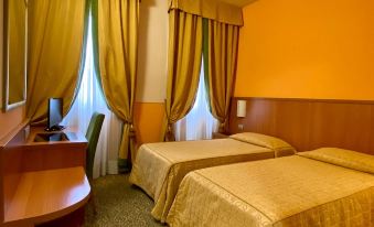 a hotel room with two beds , curtains , and a desk , giving it a cozy and inviting atmosphere at Hotel Kristall