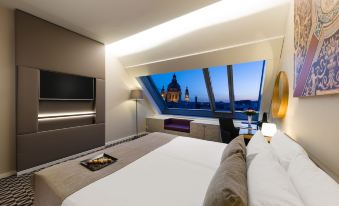 a hotel room with a large bed and a view of a cityscape through the window at Hotel Moments Budapest