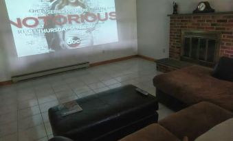 "a living room with a couch , television , and a projector displaying the movie "" notorious .""." at Roxbury Suites