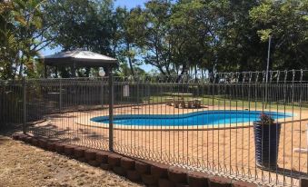 a backyard with a swimming pool surrounded by a fence , and a picnic table in the background at Hillview Motel