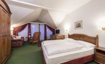 a bedroom with a large bed , wooden headboard , and a chair in the corner at Hotel Grüner Baum