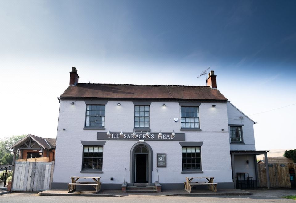 "a white building with a sign that reads "" the sanger 's arms "" is shown in front of trees" at The Saracens Head