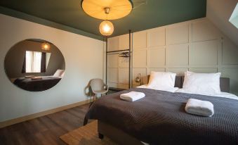 a cozy bedroom with a large bed , a round mirror on the wall , and various pieces of furniture at Mr Lewis Zandvoort