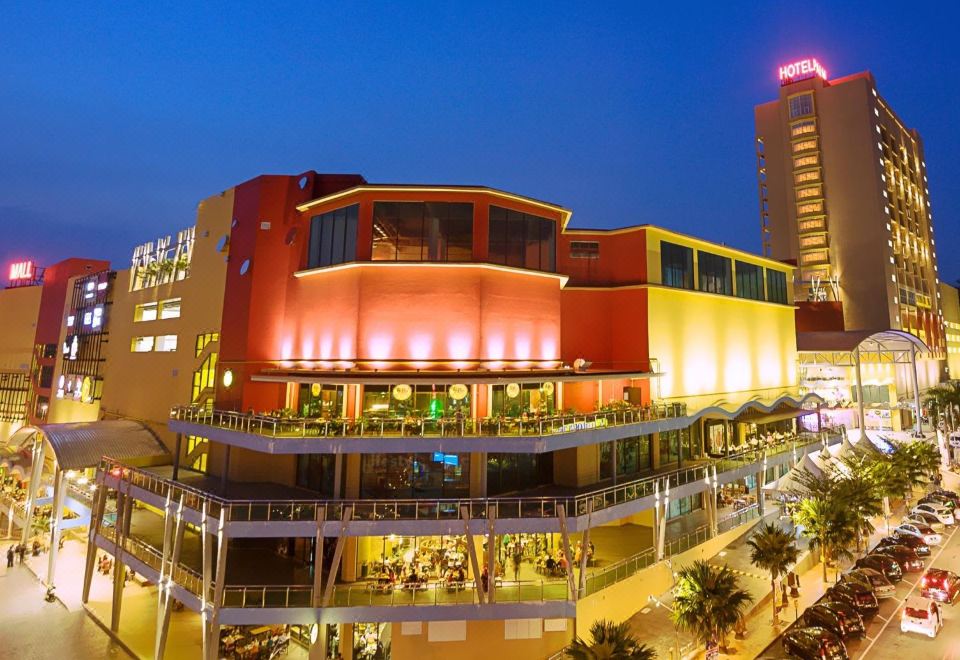 a large shopping mall with a red and orange building in the center , surrounded by other buildings and lights at Palm Seremban Hotel