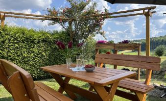 a wooden table with two chairs and a vase of flowers in front of it at Hartmann