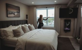 a woman standing in a hotel room , looking out the window and enjoying the view at Riverside Suites
