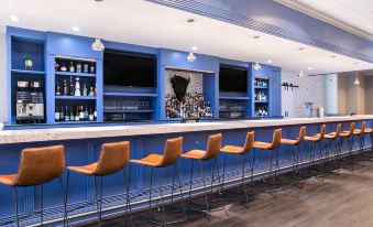 a modern bar with blue walls and brown chairs , featuring multiple televisions on the wall at Winston-Salem Marriott
