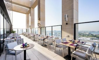 a modern restaurant with tables and chairs , a view of the city through large windows at Park Hyatt Doha
