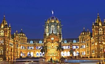 a large , ornate building with multiple domes and lights illuminating the night sky , set against a dark blue background at Courtyard by Marriott Mumbai International Airport