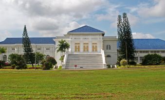 a large white building with a blue roof is surrounded by a grassy field and palm trees at KSL Hot Spring Resort