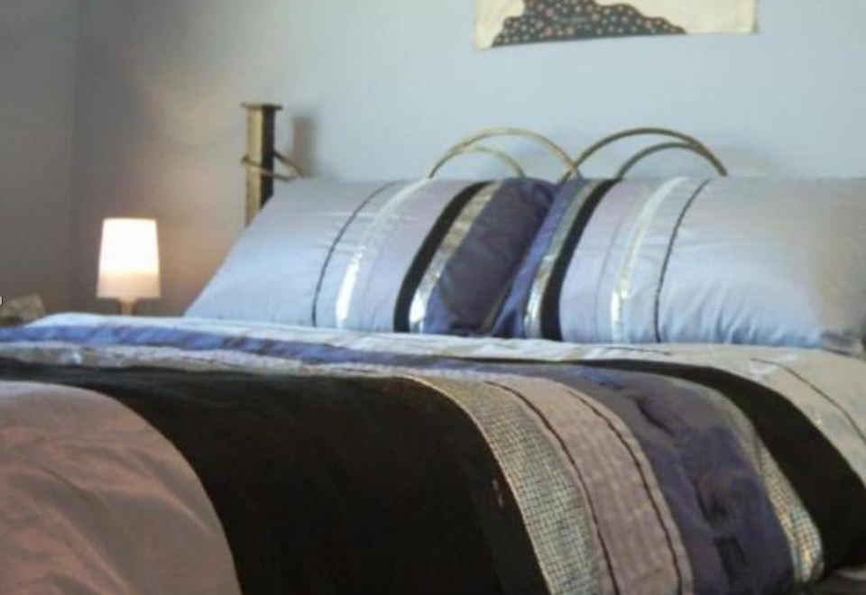 a bed with a gold headboard and black and gray pillows is shown in a bedroom at Number Twelve