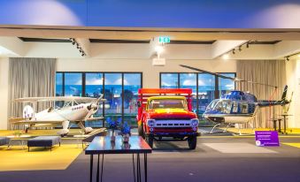 a showroom with various vehicles on display , including airplanes and a truck , under bright lights at Hyatt Place Melbourne Essendon Fields