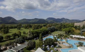 a golf course with a large pool surrounded by trees and mountains in the background at Hotel Majestic