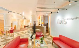 "a hotel lobby with red couches and chairs , a check - in counter , and a sign for the company "" ibis ""." at Ibis Firenze Nord Aeroporto