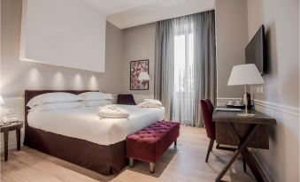 a large bed with white linens and a red headboard is in the middle of a room with a desk , chair , and window at Palazzo Castri 1874 Hotel & Spa