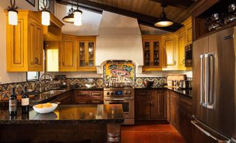 a large , well - equipped kitchen with wooden cabinets and a colorful mosaic backsplash is shown in the image at La Lomita Ranch