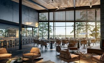 a modern , minimalist restaurant with wooden furniture and large windows offering views of the surrounding area at The Sebel Yarrawonga Silverwoods