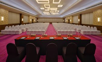 a large conference room with multiple rows of chairs arranged in a semicircle , and a podium at the front of the room at Holiday Inn Resort Goa