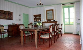 a dining room with a wooden table surrounded by chairs , and a kitchen in the background at Chateau Latour