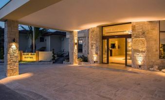 a modern building with stone columns and a glass door , illuminated by lights at night at Blue Bay Halkidiki