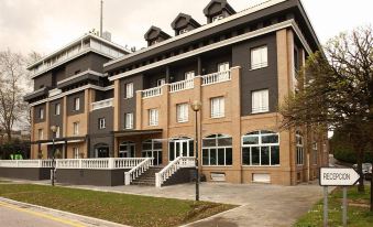 a large brown building with a white railing and balcony , situated on a street corner at Hotel Urdanibia Park