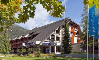 a large hotel building surrounded by trees and grass , located in a mountainous area at Hotel Kompas
