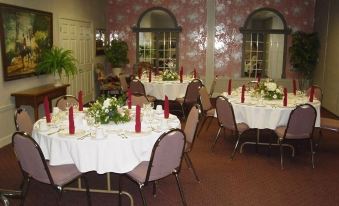a well - decorated dining room with several round tables covered in white tablecloths , set for a formal dinner at White Columns Inn