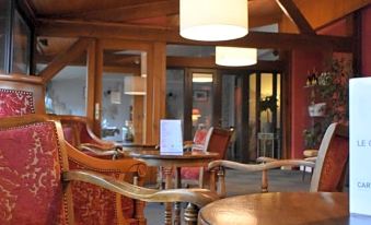 a cozy restaurant with wooden tables and chairs , red curtains , and a sign on the wall at Le Cheval Blanc - Logis Hotel