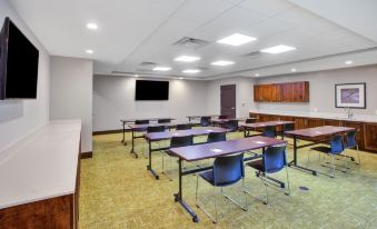 a conference room with several tables and chairs , a tv on the wall , and a wooden cabinet at Staybridge Suites Benton Harbor - ST. Joseph