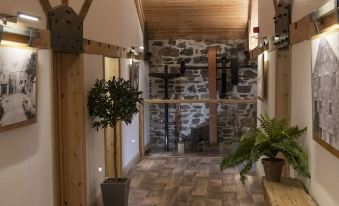 a hallway with a wooden floor and stone walls leads to a room with potted plants at Trail Lodge