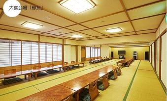 a large , empty dining room with wooden tables and chairs , and multiple windows providing natural light at Hakugei