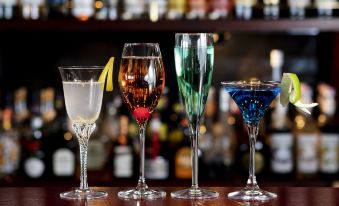 a bar counter with four different types of cocktails , including champagne , martini , and wine glasses , as well as various bottles of alcohol at Hotel Kanazawa