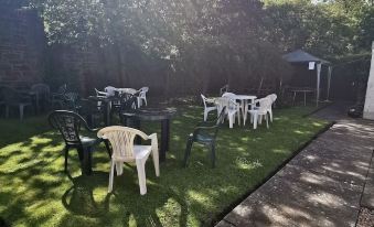 a grassy backyard with several tables and chairs set up for outdoor dining , surrounded by trees at The George Hotel