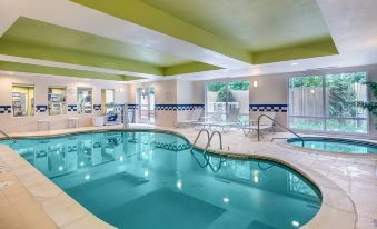an indoor swimming pool with a green ceiling , surrounded by lounge chairs and umbrellas , providing a relaxing atmosphere at Fairfield Inn & Suites Worcester Auburn