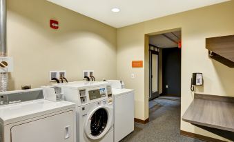 a laundry room with three washers and two dryers placed next to each other , along with a dryer in the corner at Home2 Suites by Hilton Dickson City Scranton