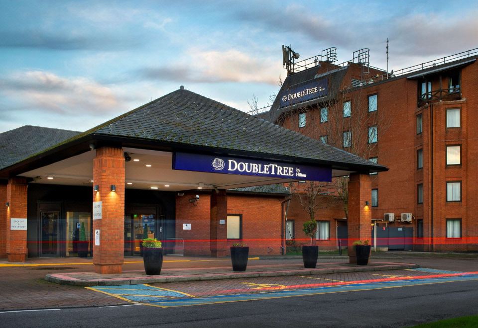 a hotel with a blue sign above the entrance , indicating that it is a double tree hotel at DoubleTree by Hilton Manchester Airport