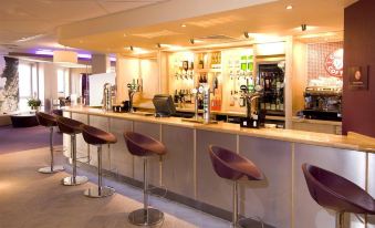 a modern bar with various bottles of alcohol on the counter and several stools surrounding it at Premier Inn Sheffield City Centre (St Mary's Gate)